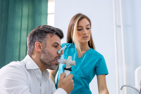 woman in scrubs helping man with breathing treatment