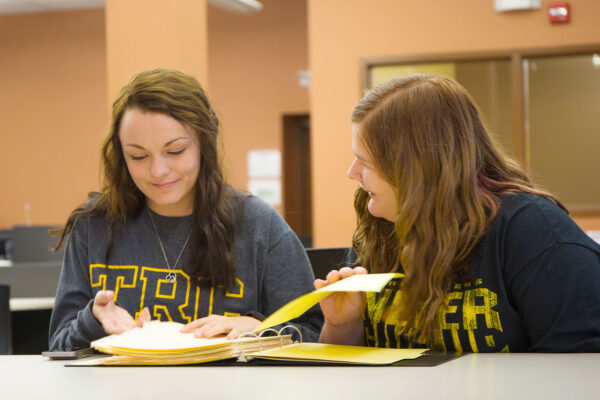 a couple of girls looking at a book