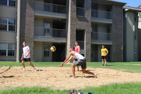 four students playing volleyball
